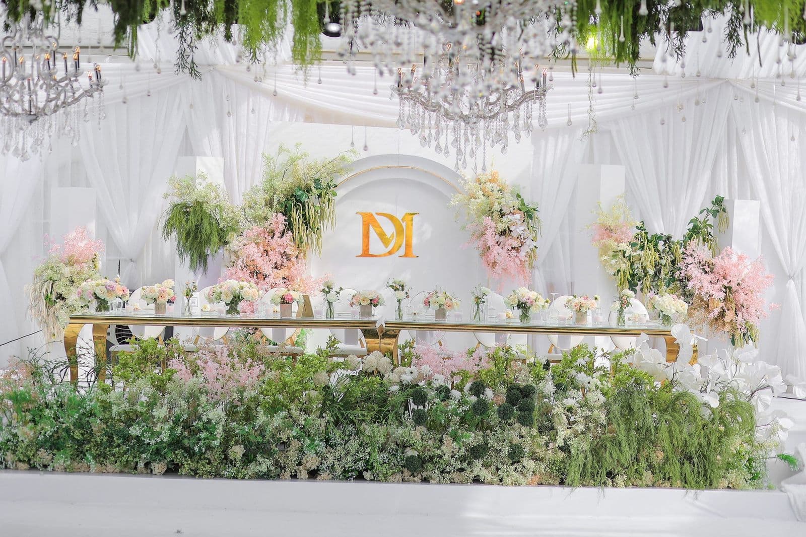 Luxurious head table with DM monogram, pink florals and crystal chandeliers