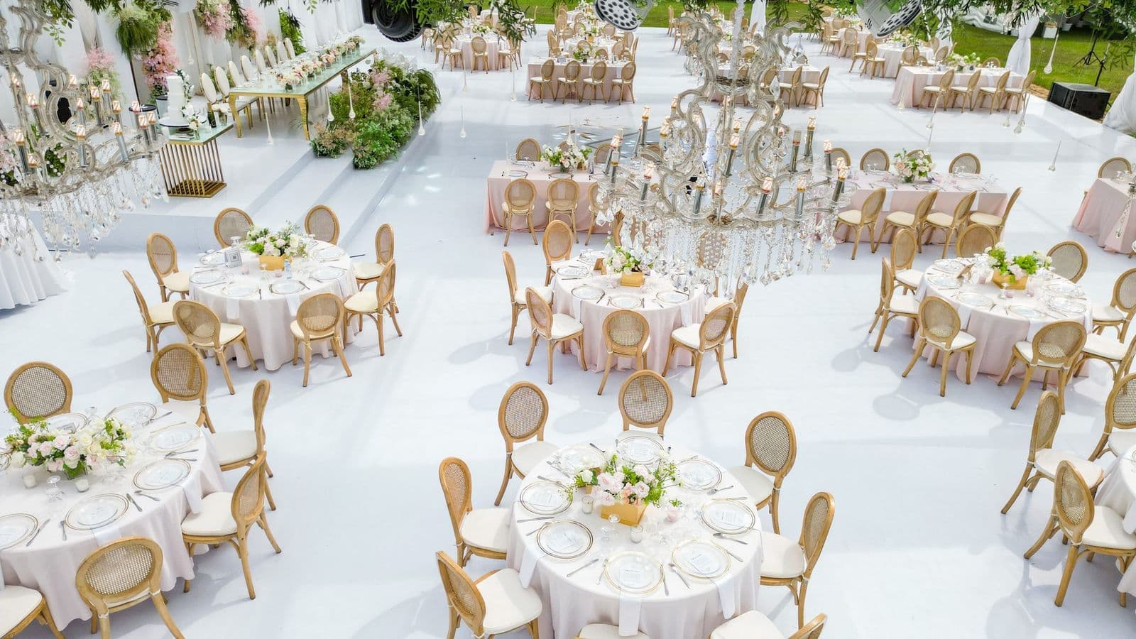 Aerial view of luxurious wedding reception with blush linens, gold chairs, and crystal chandeliers